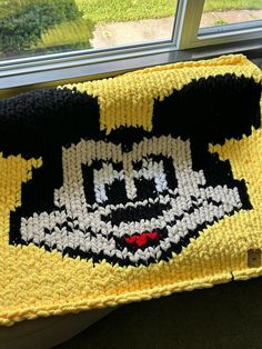 a crocheted mickey mouse blanket sitting on top of a window sill