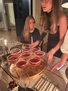 two women standing in front of a table with wine glasses and desserts on it