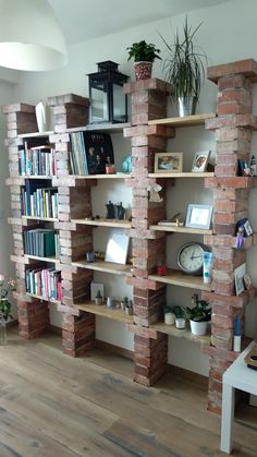 a bookshelf made out of bricks in the corner of a room with a clock on it