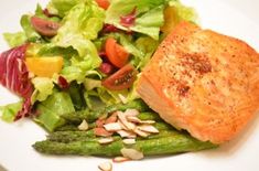 salmon and asparagus on a white plate with almonds, lettuce