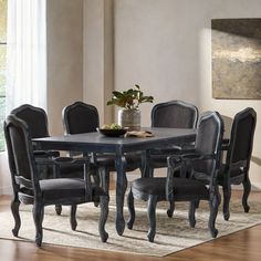 a dining room table with black chairs and a potted plant on top of it