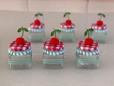 there are four small cakes with cherries on the top and one has a green leaf