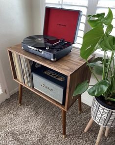 a record player sitting on top of a wooden table next to a potted plant