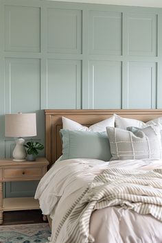 a bed with white and blue pillows in a bedroom next to a wall that has green paneling on it