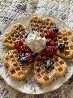 waffles topped with berries and whipped cream on a floral tablecloth covered plate