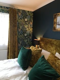 a bed with two green pillows on top of it next to a painting and window