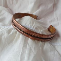 a close up of a wooden bracelet on a white cloth covered bed sheet with an object in the background