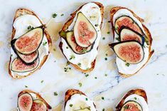 three pieces of bread with figs and cream cheese on them sitting on a marble surface