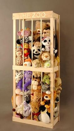 a wooden shelf filled with lots of stuffed animals on top of a floor next to a wall