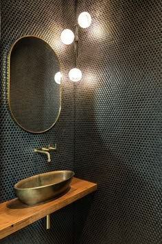 a bathroom sink sitting under a mirror next to a wooden counter with lights on it