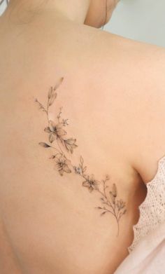 the back of a woman's shoulder with small flowers on her left side,