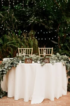 the table is set up with chairs and greenery