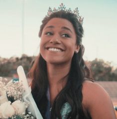 a woman wearing a tiara holding a bouquet of flowers