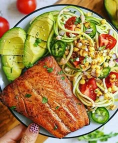 a plate with salmon, zucchini noodles and tomatoes