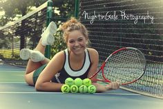 a woman laying on the tennis court with her racquet and balls in front of her