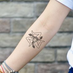 a woman's arm with a tattoo on it and a brick wall behind her