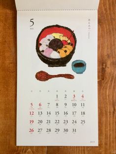 a calendar with an image of a bowl of food and spoon on the table next to it