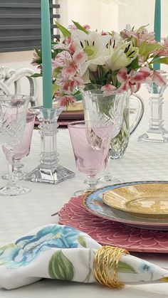 the table is set with pink and white flowers in vases, napkins, and glasses