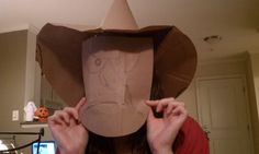 a woman wearing a brown paper hat with an elephant drawn on it's face