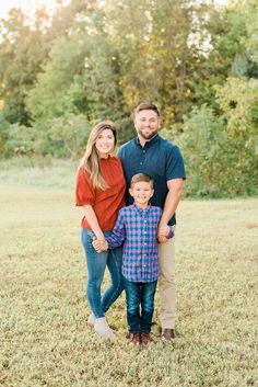 an image of a family posing for a photo in the grass with trees in the background