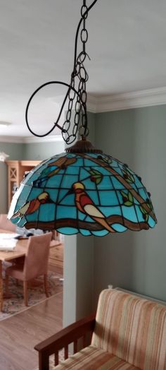 a stained glass light hanging from the ceiling in a dining room with chairs and table