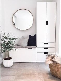 a room with white furniture and a round mirror on the wall, along with a potted plant