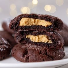 chocolate cookies with peanut butter in the middle stacked on top of each other, ready to be eaten