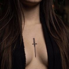 a woman's chest with a cross tattoo on her left side, and a knife in the middle