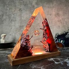 a wooden stand with two sculptures on it and a light in the shape of a triangle