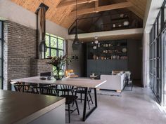 a dining room table and chairs in front of a brick wall with open windows on the side