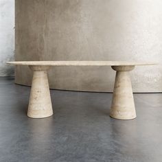 two white marble pedestals sitting next to each other on a cement floor in front of a concrete wall