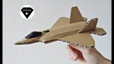 a hand holding up a cardboard model of a jet plane with a mouse on it