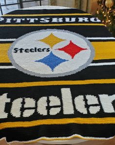 a blanket with the pittsburgh football team on it is sitting on a table next to a christmas tree