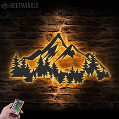 a person holding a remote control in front of a wall with a mountain scene on it