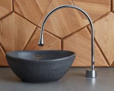 a black bowl sink sitting on top of a counter next to a faucet