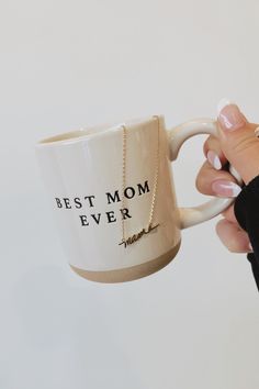 a woman holding a coffee mug with the words best mom ever written on it, in front of a white background