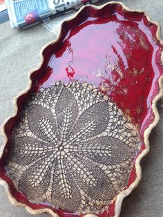 a red bowl sitting on top of a table next to a magazine and some scissors