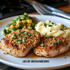 two pieces of meat on a plate with mashed potatoes and garnishes