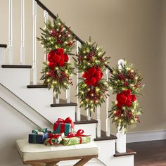 christmas decorations on the banisters and stairs in front of a stair case with presents