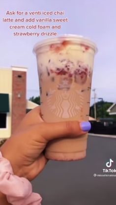 a woman holding up a cup of ice cream in front of a building with the caption ask for a vein iced chai latte and add vanilla sweet creme