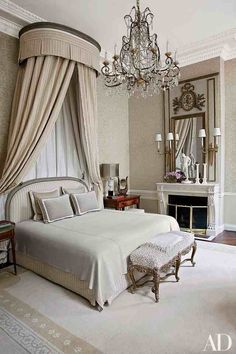 a white bed sitting in a bedroom next to a chandelier and a mirror