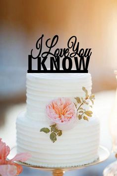 a wedding cake with the words i love you know on it and a pink flower