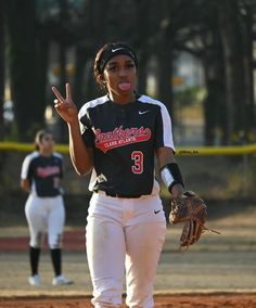 a female baseball player giving the peace sign while holding a catcher's mitt