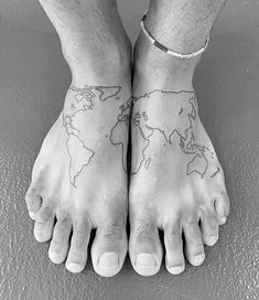 a person's feet with tattoos on them and the world map tattooed on their ankles