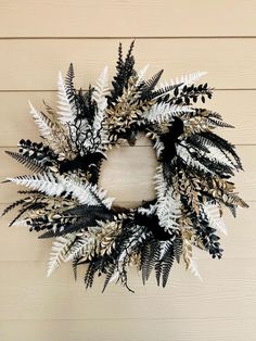 a wreath with white and black leaves hanging on a wall