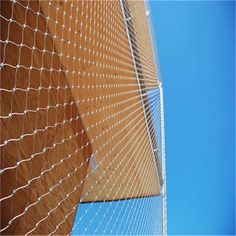 the side of a building with a chain link fence on it and a blue sky in the background