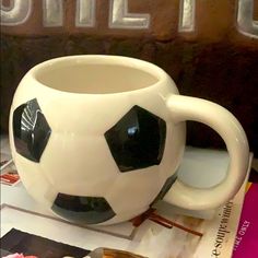 a white and black soccer ball mug sitting on top of a table next to books