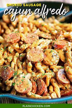 pasta with sausage and tomatoes in a blue bowl on a wooden table, ready to be eaten