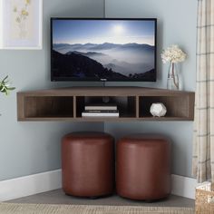 a flat screen tv sitting on top of a wooden shelf next to two brown stools