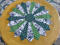 a wooden table topped with a green and white flower on top of a cloth covered plate